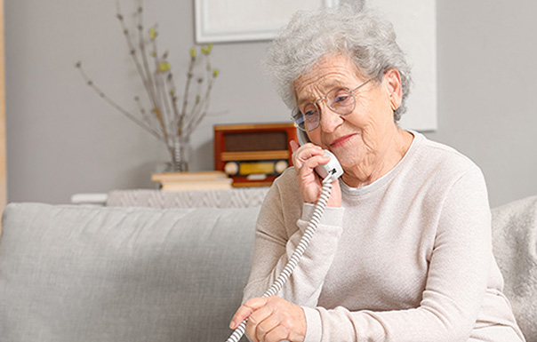 Vieille dame en conversation téléphonique avec un bénévole ABDF